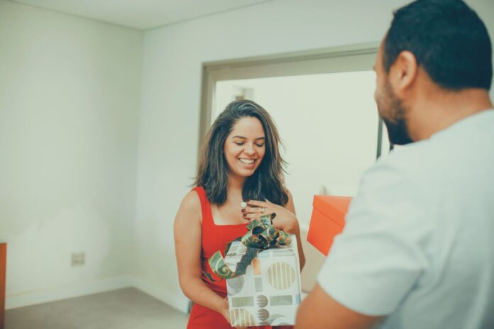 Birthday gifts for women, hands exchanging a wrapped gift box.