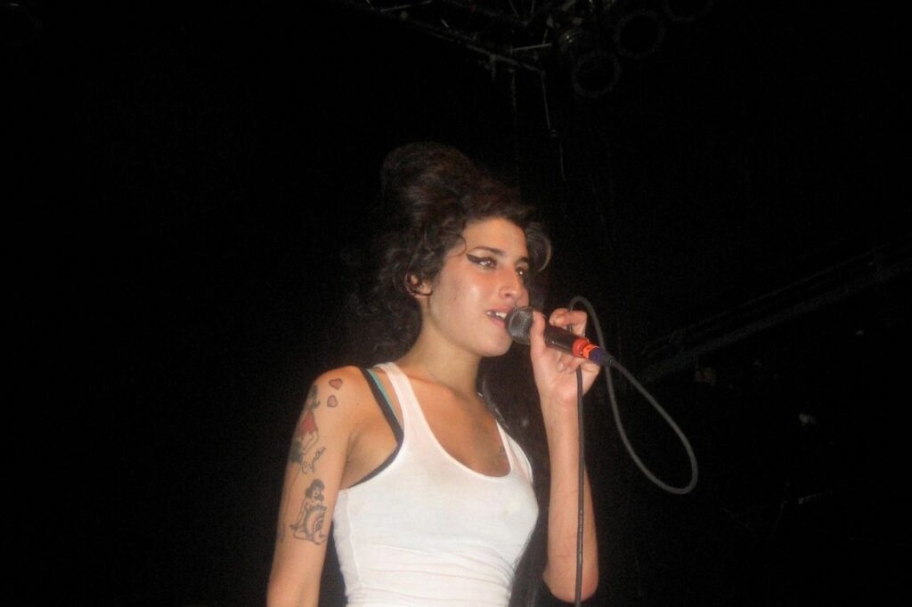 Amy Winehouse performing live on stage, an emotional moment that reflects her story in the Amy Winehouse Biography.