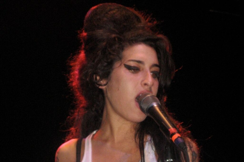 Amy Winehouse performing live on stage, a powerful moment that reflects her journey in the Amy Winehouse Biography.