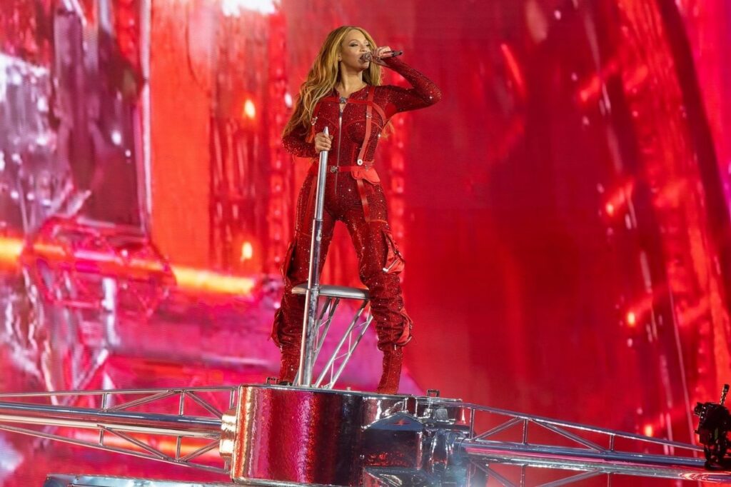 Beyoncé performing live in a red outfit during her solo career, featured in Beyoncé Biography, showing her confidence and artistic reinvention on stage.