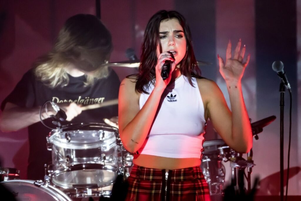 Dua Lipa performing live during a concert, singing her hit songs with passion and confidence on stage.