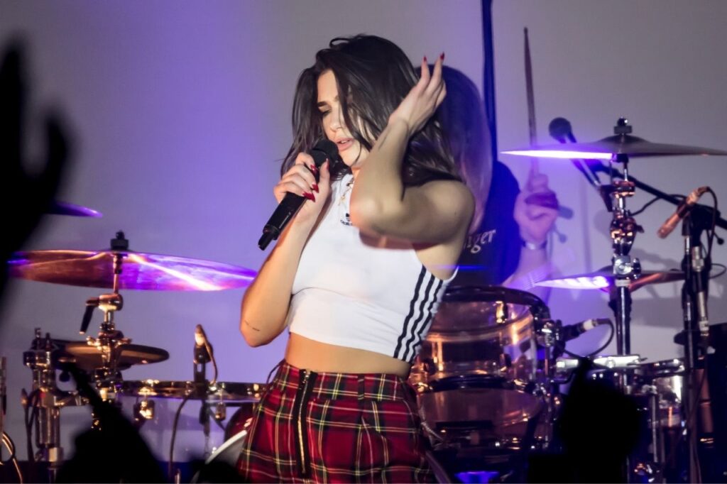 Dua Lipa performing live during an early concert, singing on stage with passion and energy.
