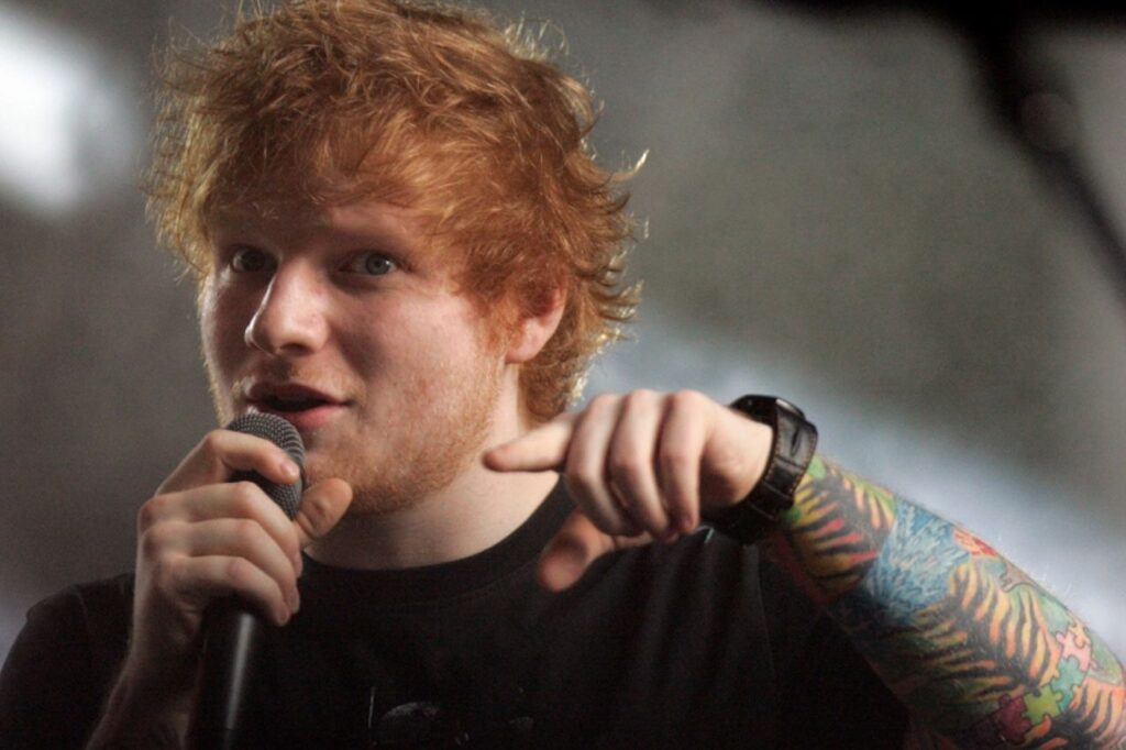 Ed Sheeran performing live during Divide Deluxe album tour with microphone in hand