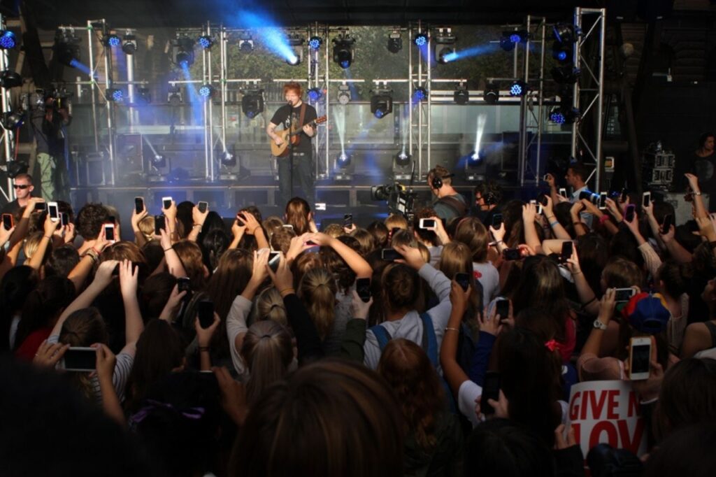 Ed Sheeran performing live in front of a large crowd during a concert
