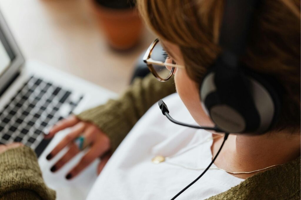 Woman wearing headphones watching music on laptop, concept of video song streaming sites.